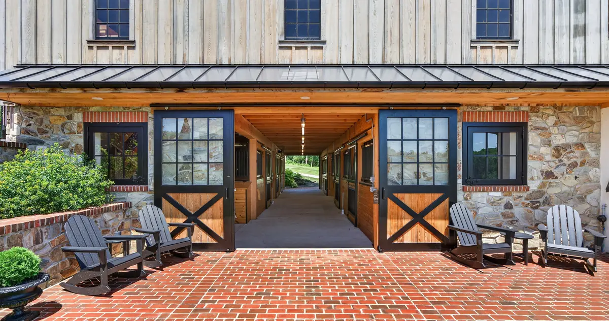 Covered deck of The Barn with wagon-wheel chandelier, timber trusses, and treetop views