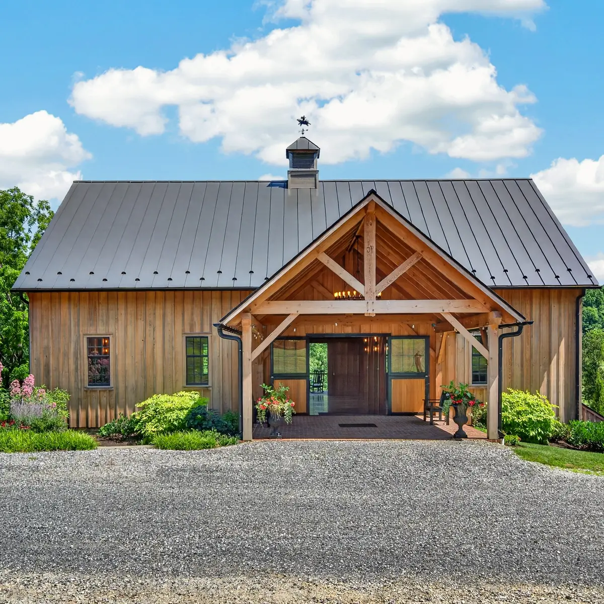 Front elevation of The Barn with timber-frame entry, cupola, and perennial gardens